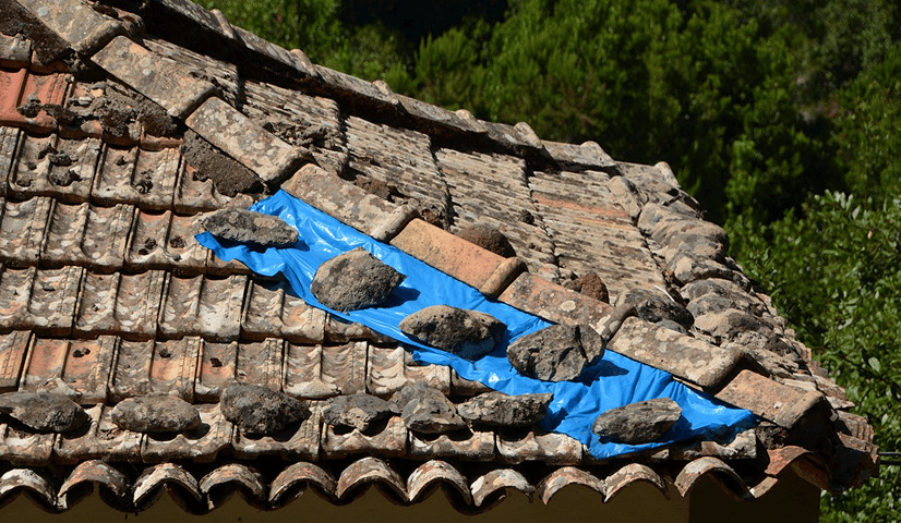 damages stone tile roof with plastic covering